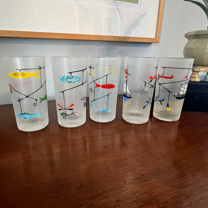 Set of five vintage-style fishing-themed glasses on a wooden surface.