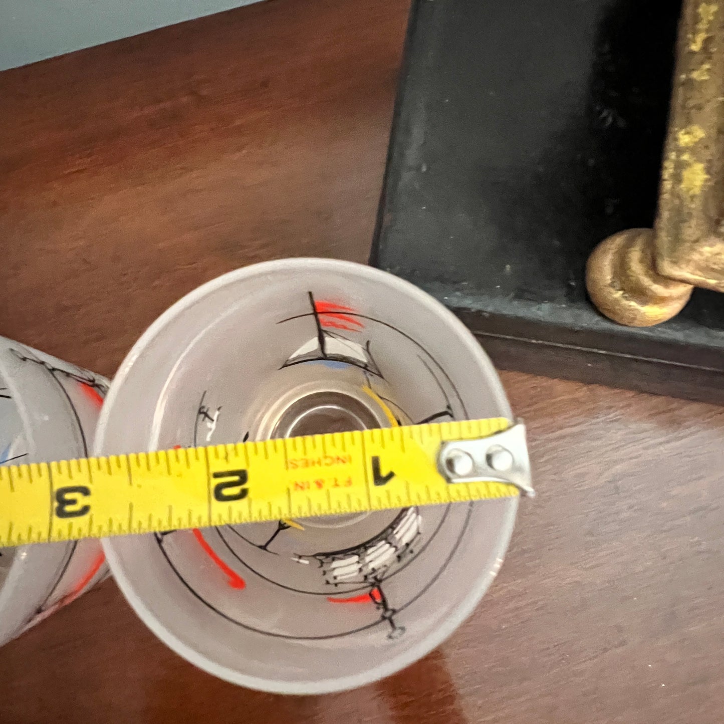 Close-up of a glass with a yellow measuring tape around it on a wooden surface.