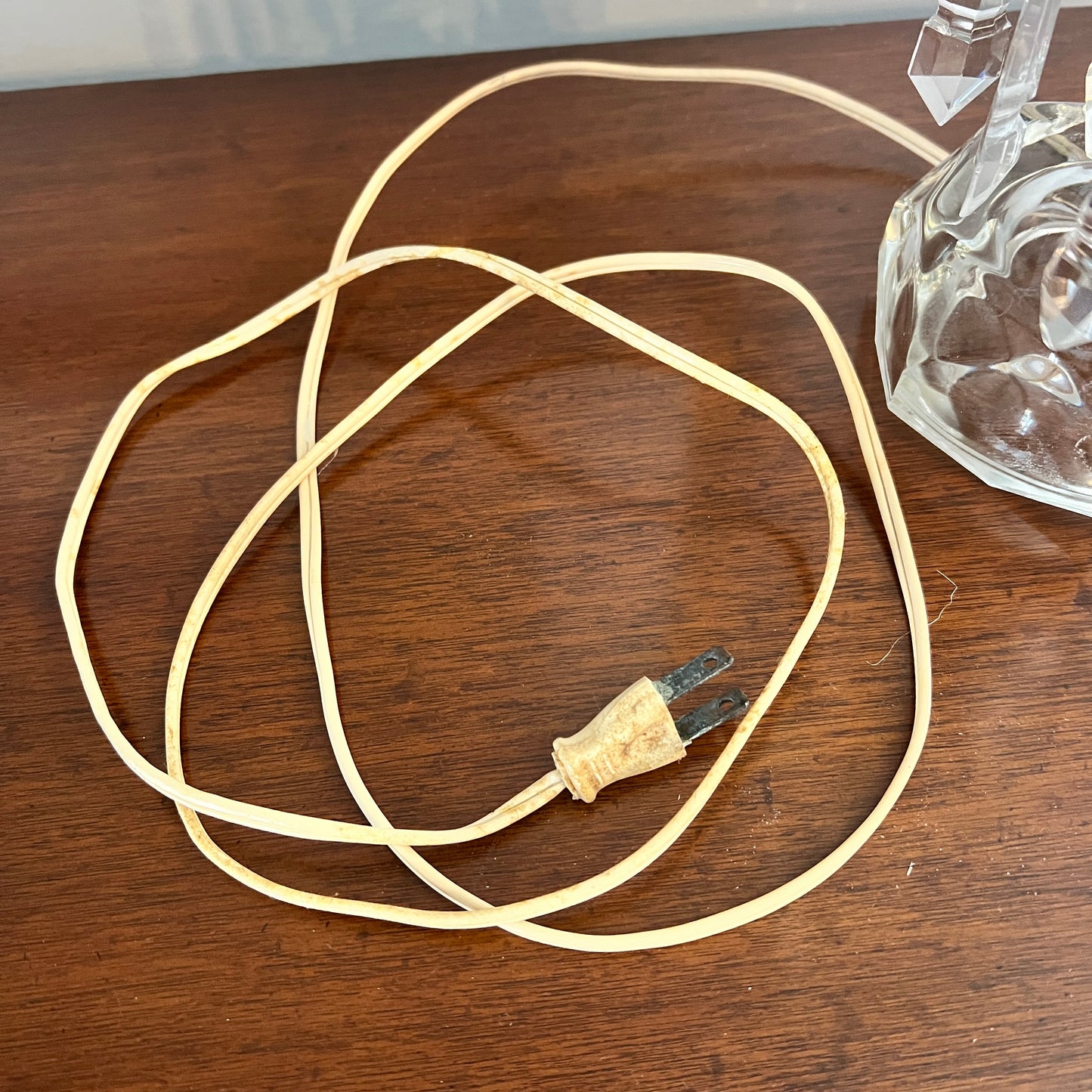 Coiled beige cable with a plug on a wooden surface