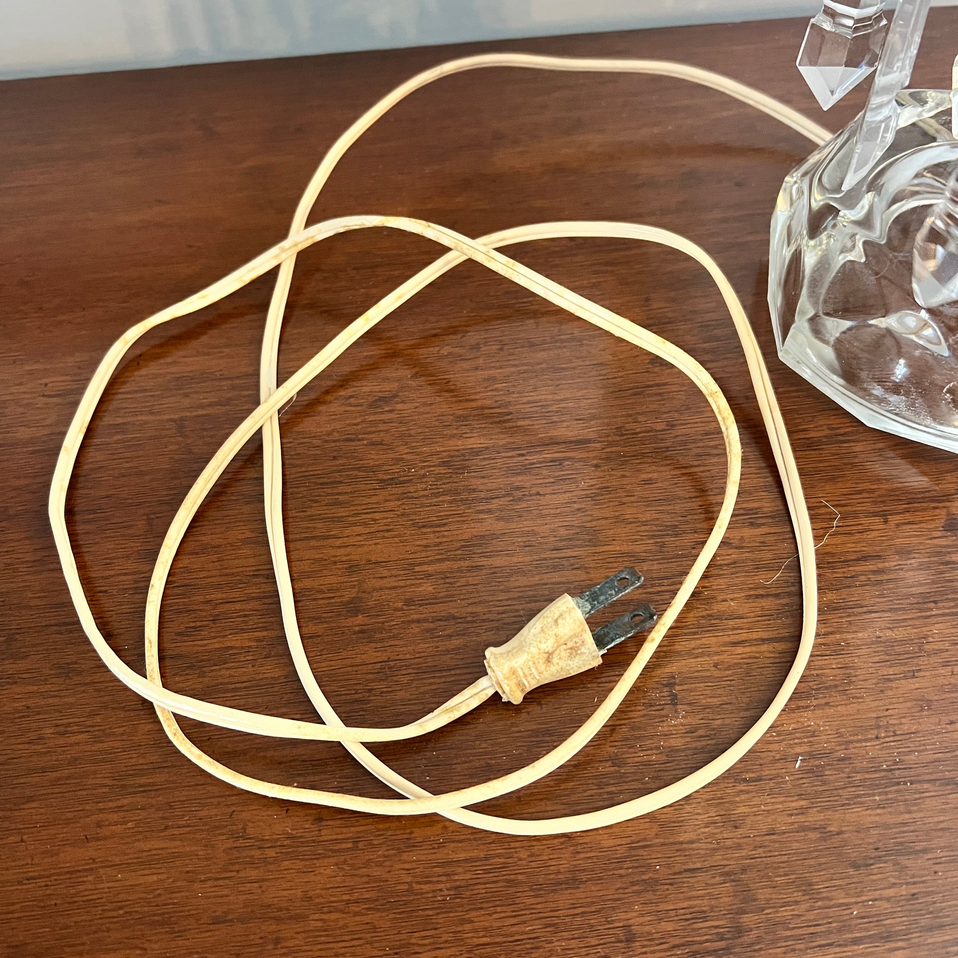 Coiled beige cable with a plug on a wooden surface