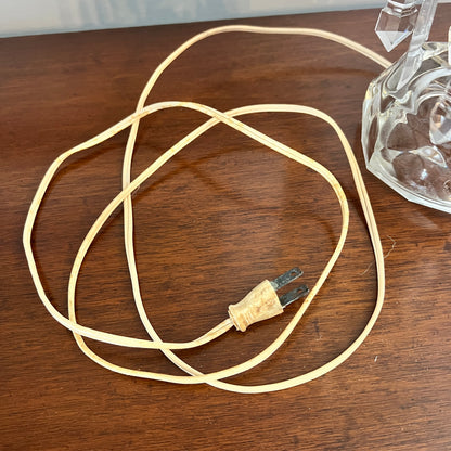 Coiled beige cable with a plug on a wooden surface