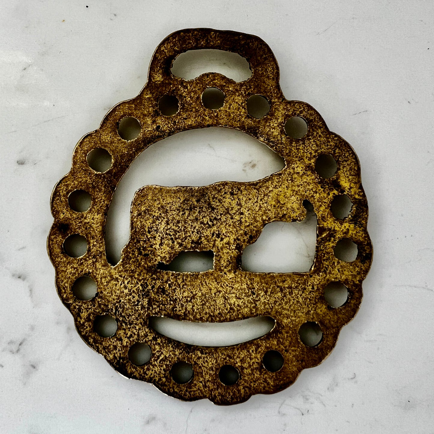 Decorative brass cow silhouette on a white marble surface