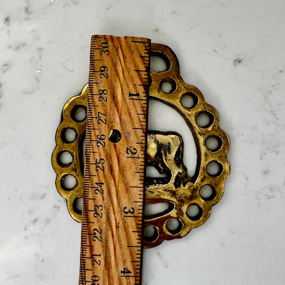 Decorative brass and wood object with a ruler for scale on a marble surface