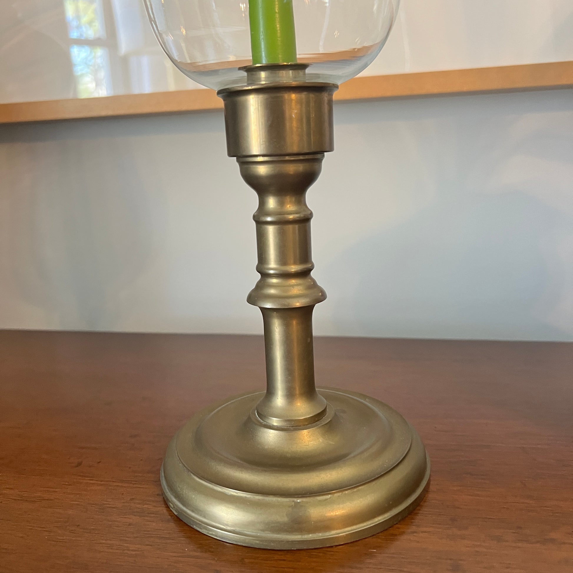 Brass candlestick with a clear glass holder on a wooden surface