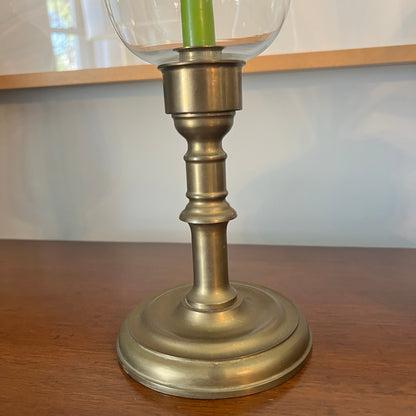 Brass candlestick with a clear glass holder on a wooden surface