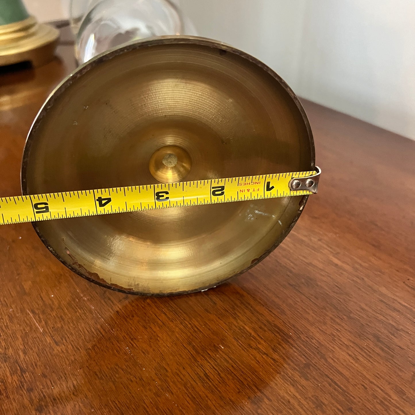 Brass object with a measuring tape indicating its size on a wooden surface