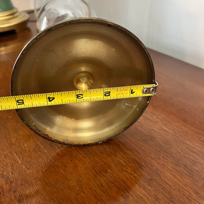 Brass object with a measuring tape indicating its size on a wooden surface