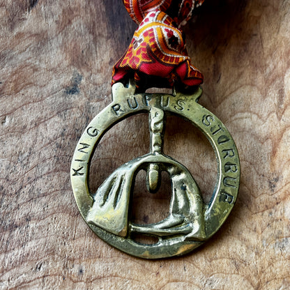 Bronze pendant with engraved text on a wooden surface
