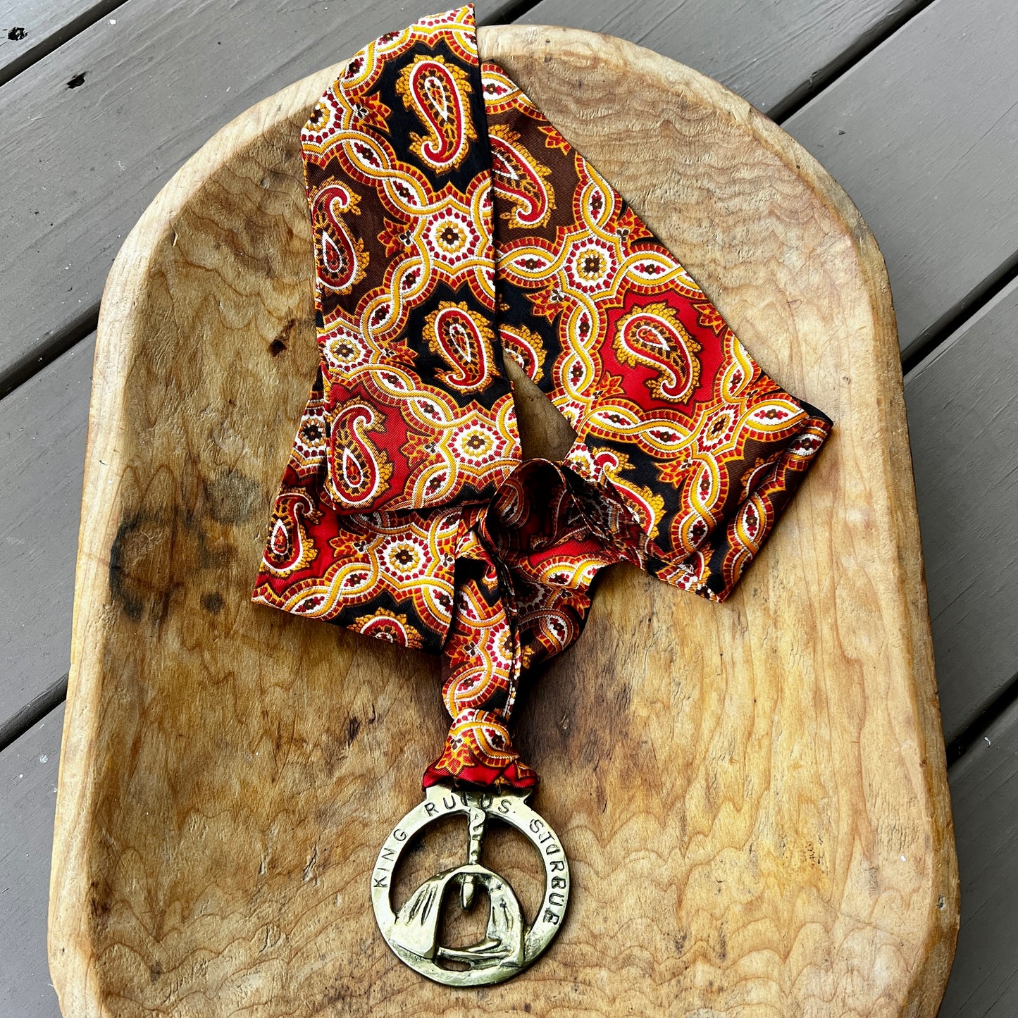 Patterned scarf with a metal pendant on a wooden surface