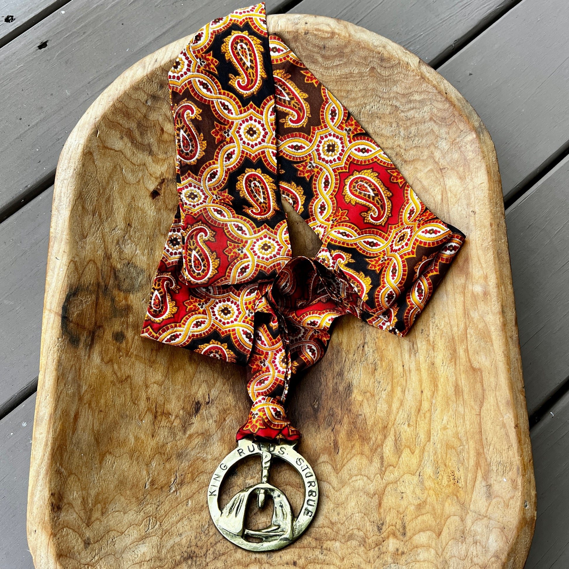 Patterned scarf with a metal pendant on a wooden surface