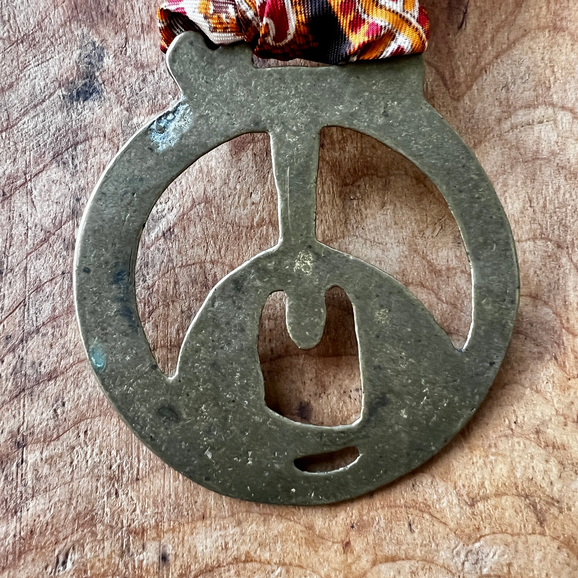 Back of Vintage King Rufus Stirrup brass medallion on wooden background