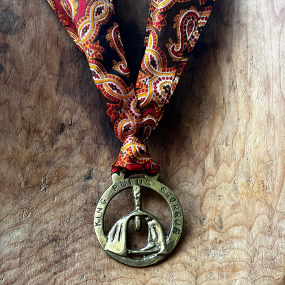 Medal with a stirrup design and 'King Ruffus Stirrup' text on a patterned ribbon against a wooden background