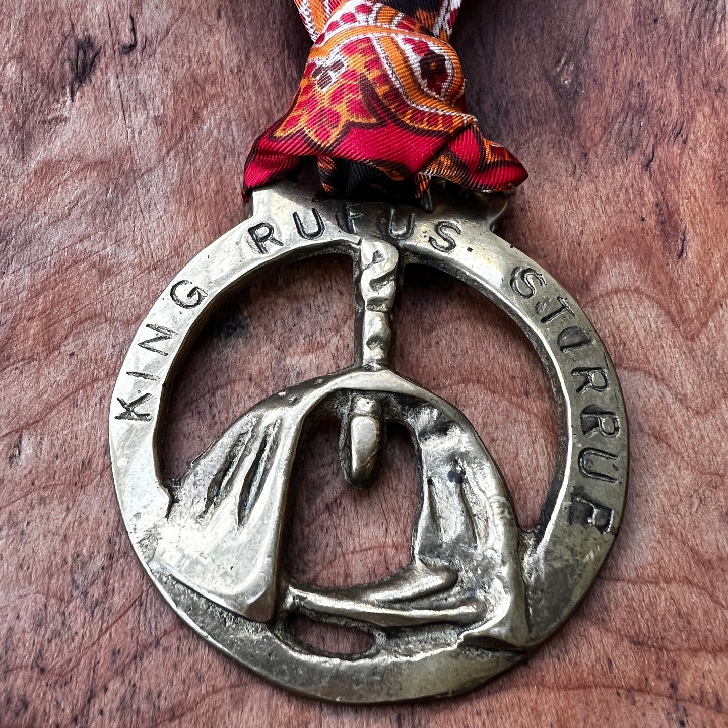 Brass pendant with engraved text on a wooden surface