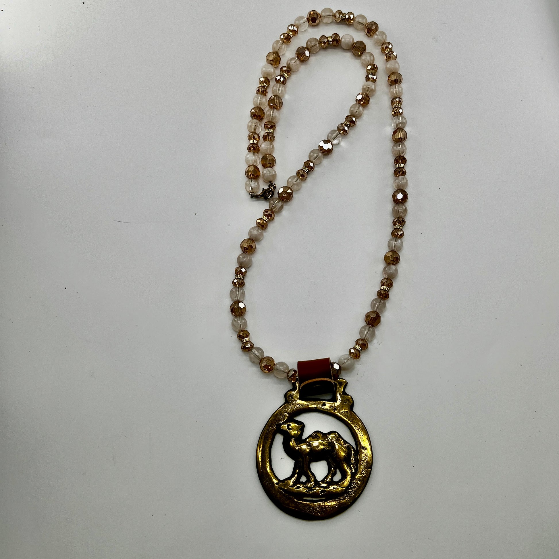 Vintage camel horse brass medallion on double-strand neutral beaded necklace with caramel leather on connector. on white background