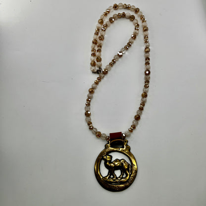 Vintage camel horse brass medallion on double-strand neutral beaded necklace with caramel leather on connector. on white background