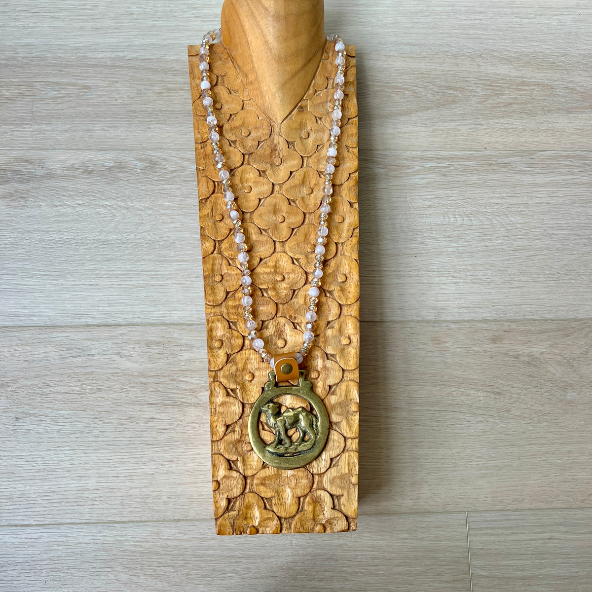 Necklace with a gold pendant on a wooden stand against a wooden background
