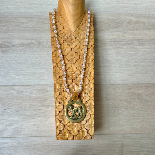 Necklace with a gold pendant on a wooden stand against a wooden background