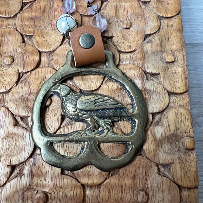 Decorative metal keychain with bird design on a wooden surface