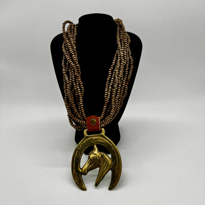 Vintage horse brass medallion attached to multi-strand wooden bead necklace with caramel leather connector.