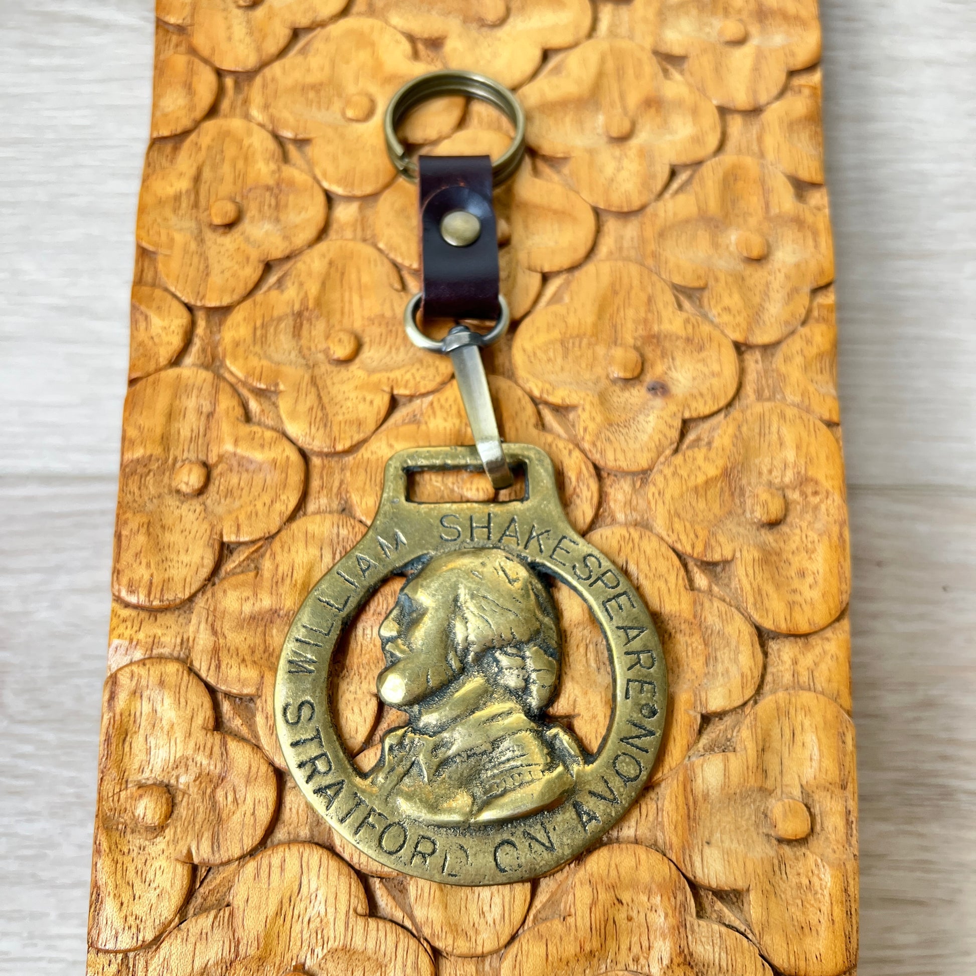 Bronze keychain with William Shakespeare's portrait on a wooden surface