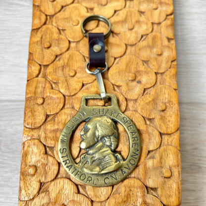 Bronze keychain with William Shakespeare's portrait on a wooden surface