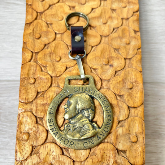 Bronze keychain with William Shakespeare's portrait on a wooden surface