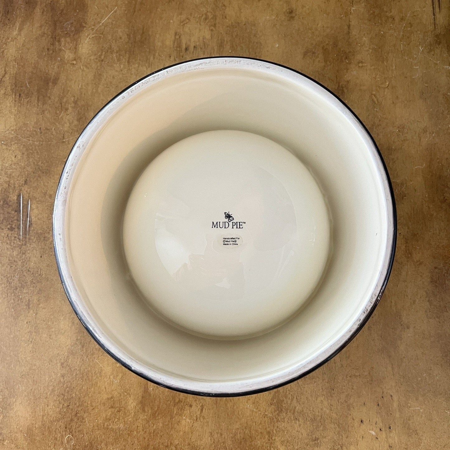 White ceramic bowl with black rim on a brown surface