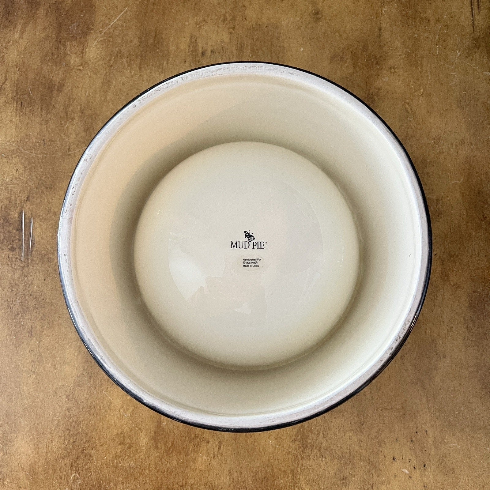 White ceramic bowl with black rim on a brown surface