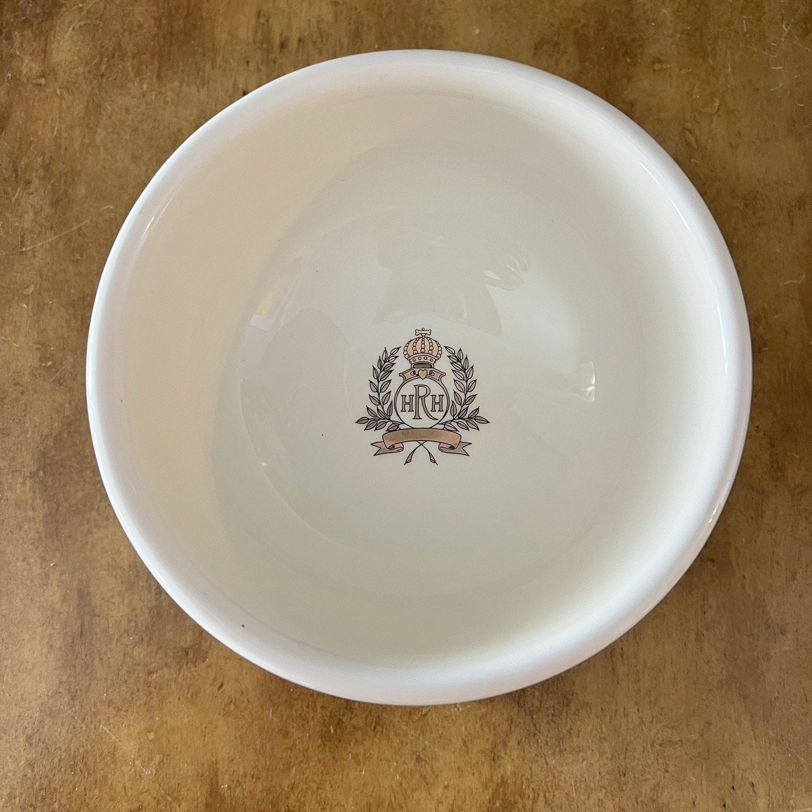 White bowl with a decorative emblem on a brown surface