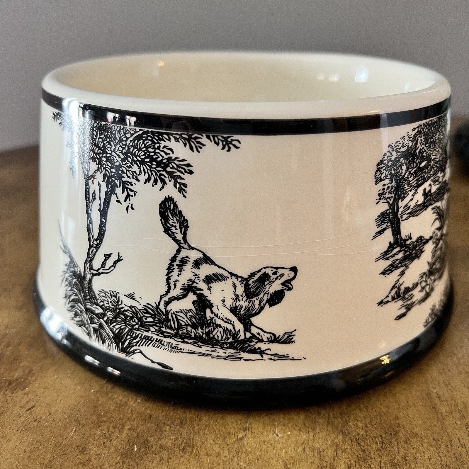 Ceramic bowl with black and white dog illustration on a wooden surface