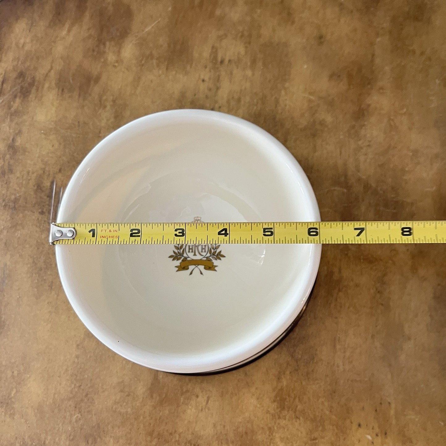 White bowl with a measuring tape around it on a brown surface