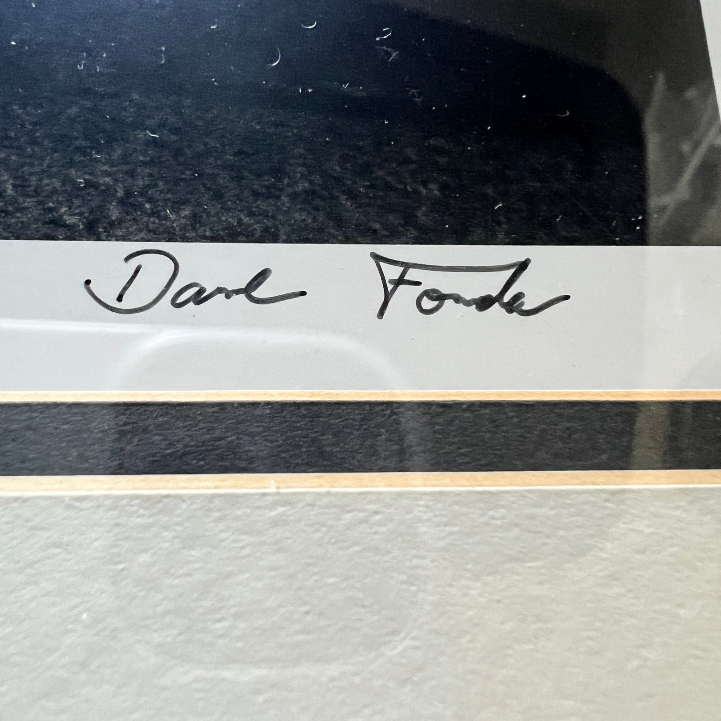 Close-up of a framed or mounted artwork with a white signature strip reading 'Dave Fonda' in black script, above a black horizontal band and a light textured surface below.