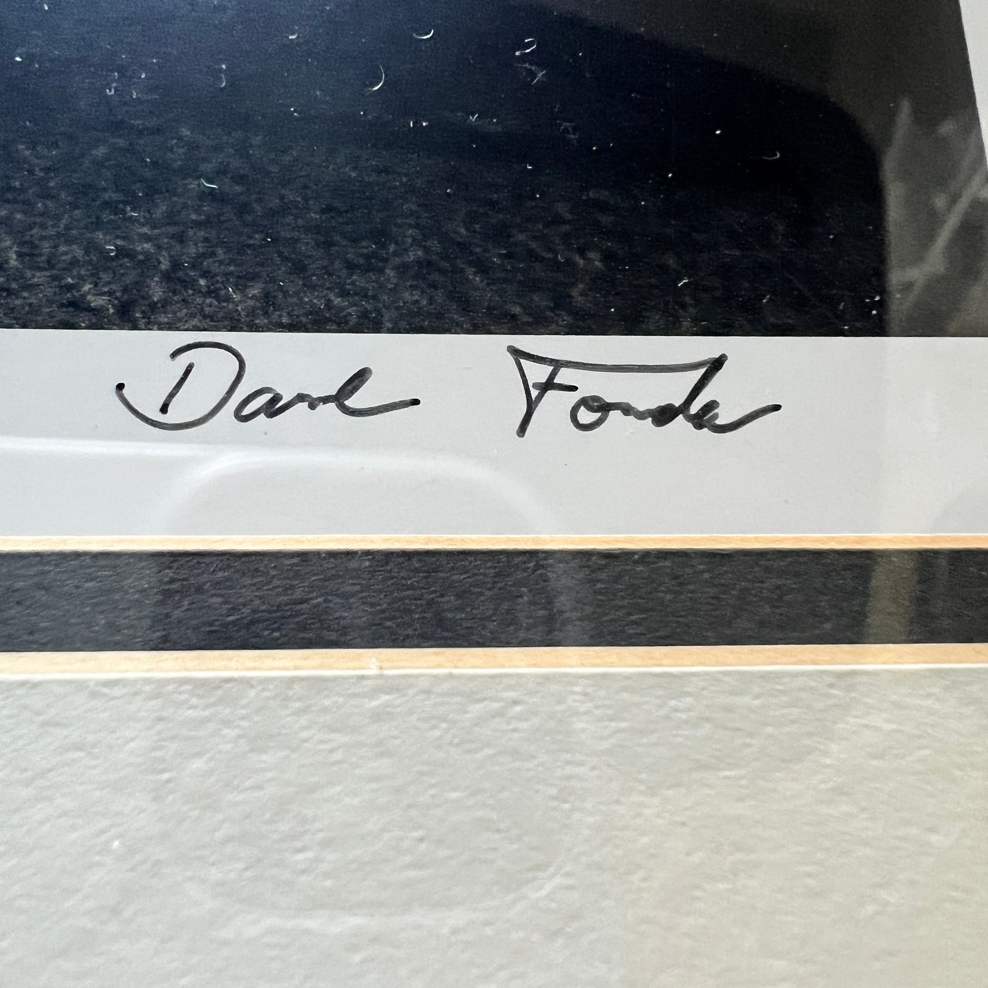 Close-up of a framed or mounted artwork with a white signature strip reading 'Dave Fonda' in black script, above a black horizontal band and a light textured surface below.