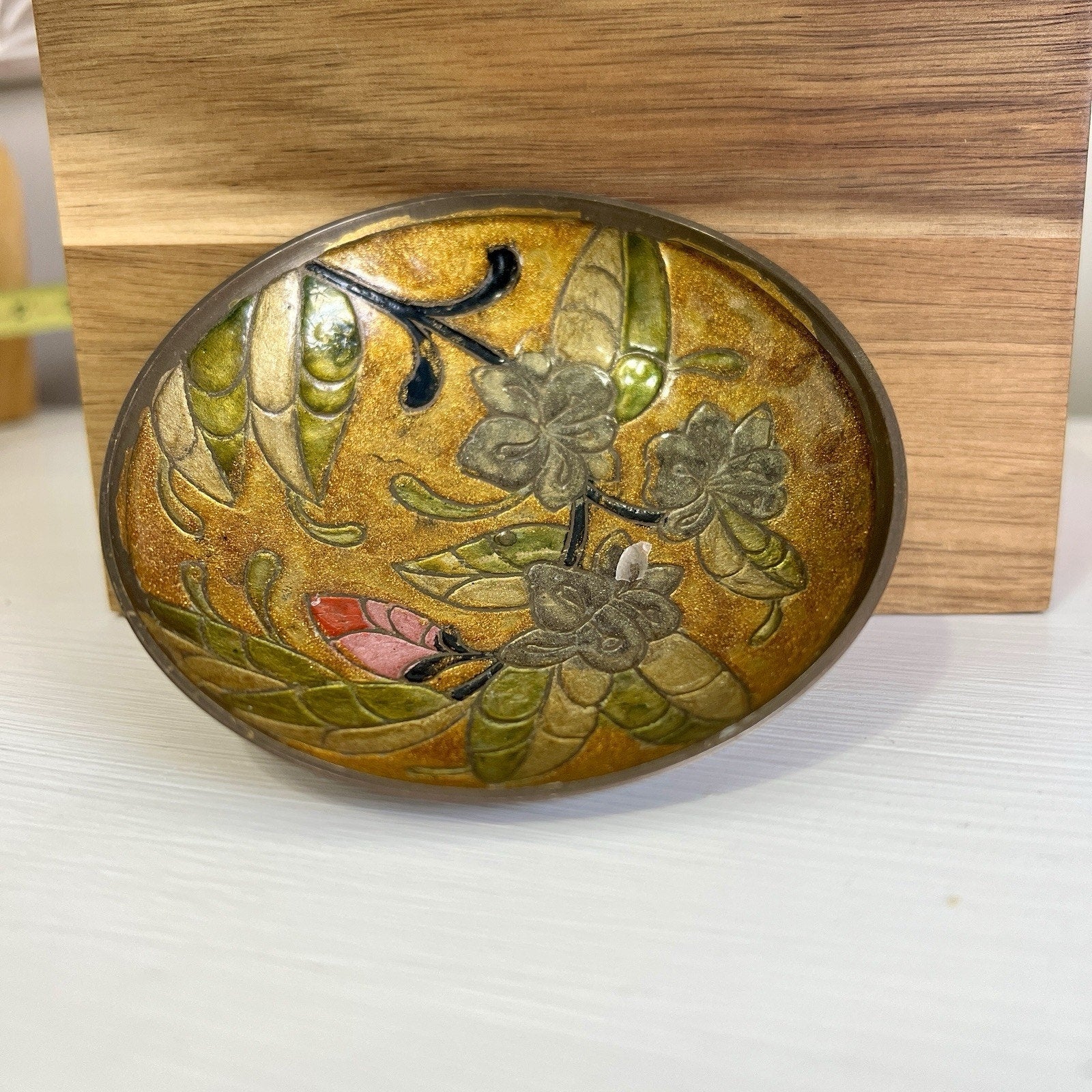 Decorative brass bowl with floral design on a wooden stand