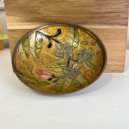 Decorative brass bowl with floral design on a wooden stand