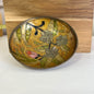 Decorative brass bowl with floral design on a wooden stand