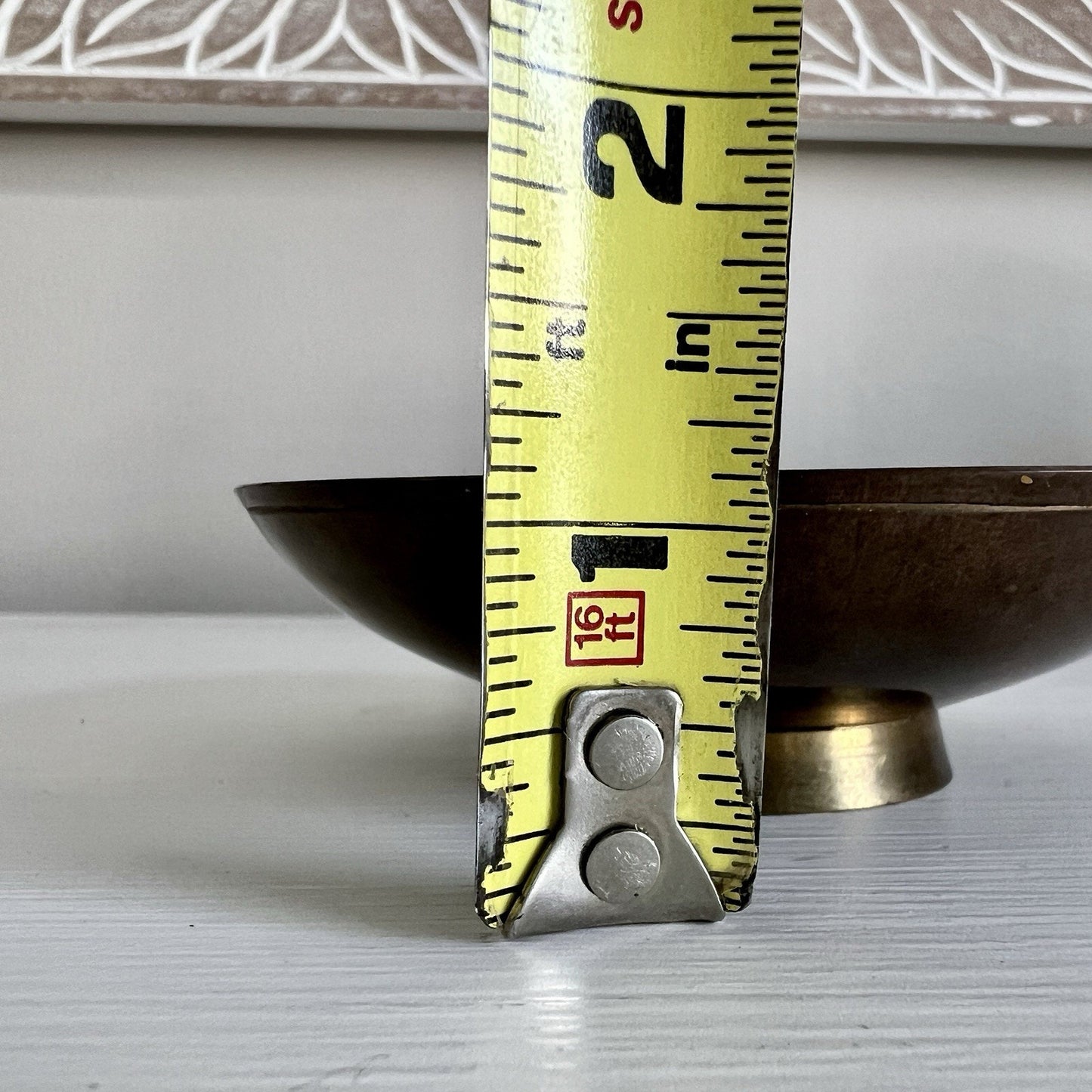 Measuring tape extended over a metallic object on a light background