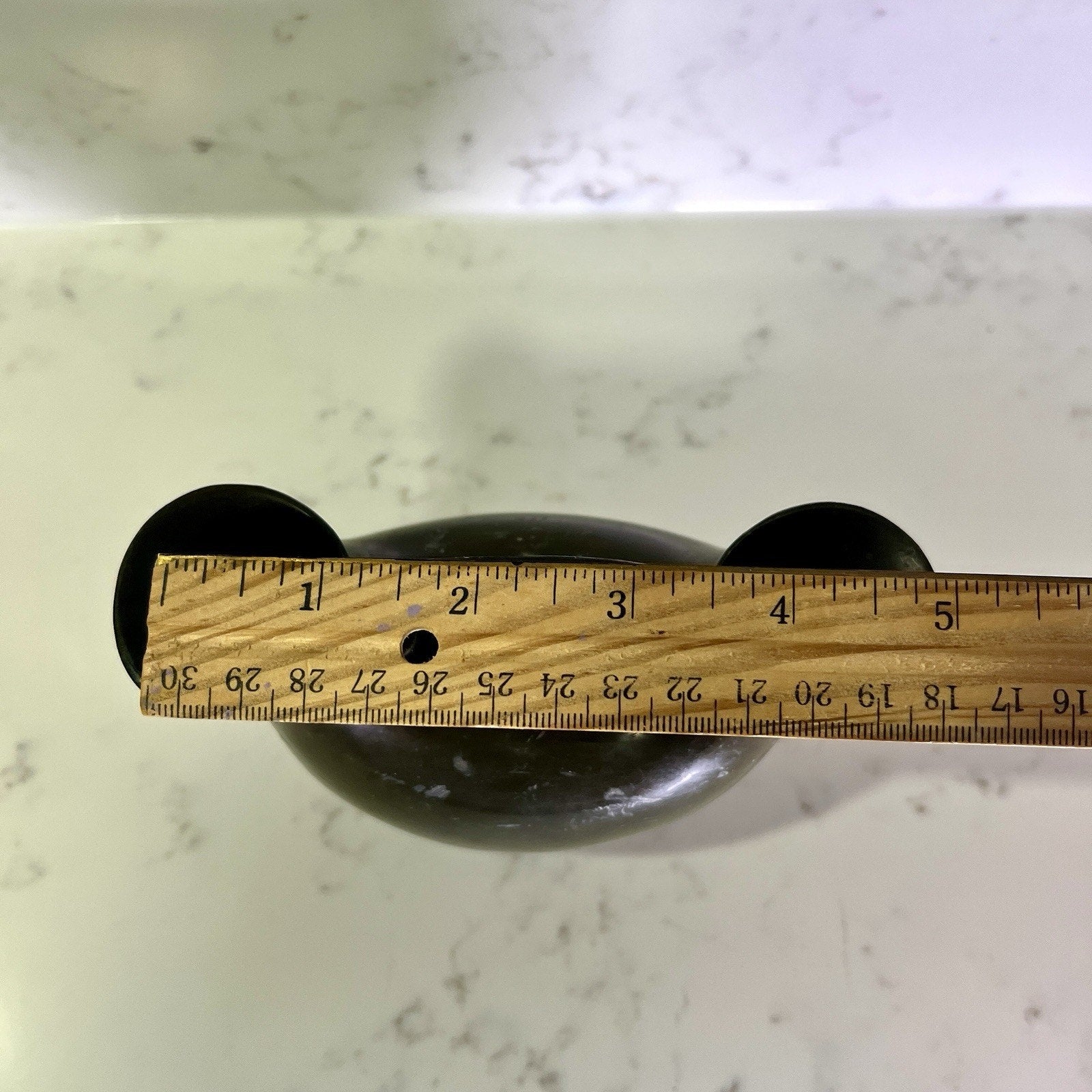 double spout vase with a wooden ruler for scale on a marble surface
