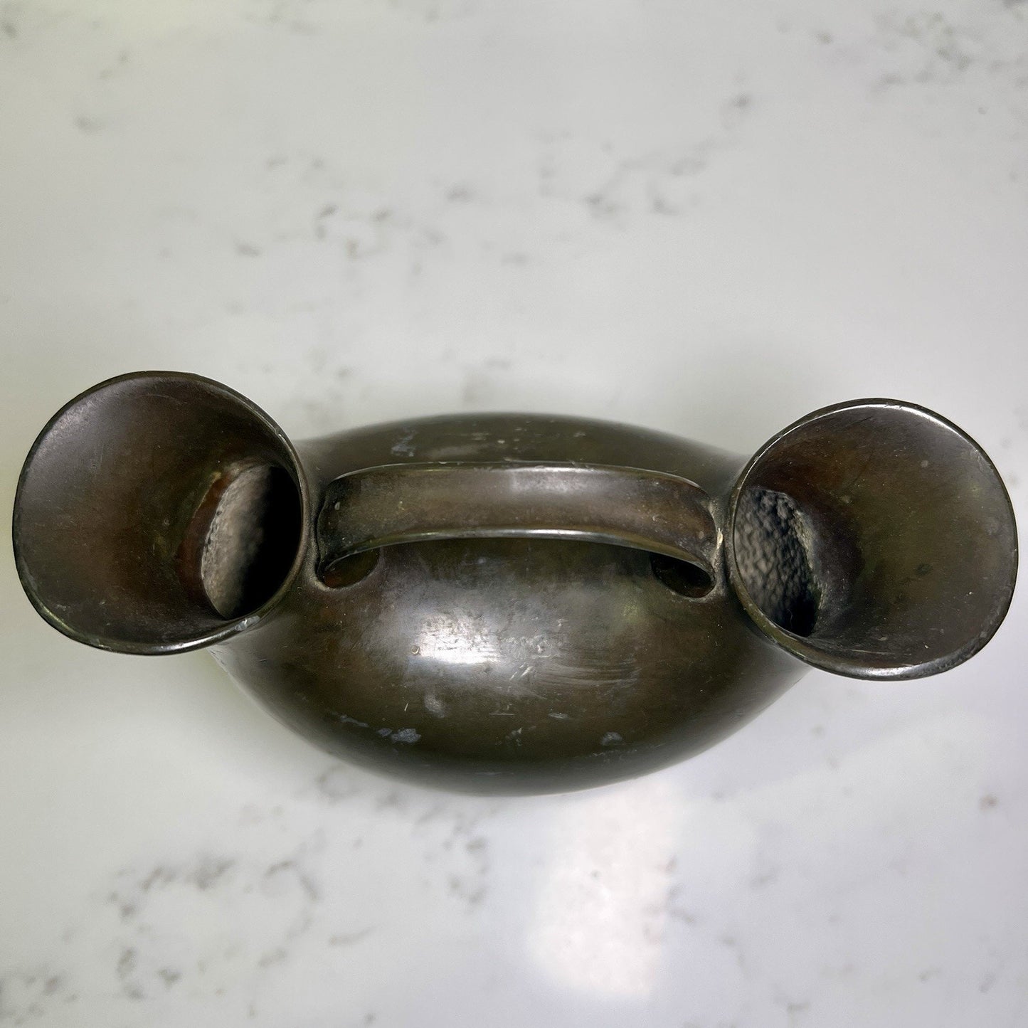 Vintage metal double spout vase  on a marble surface