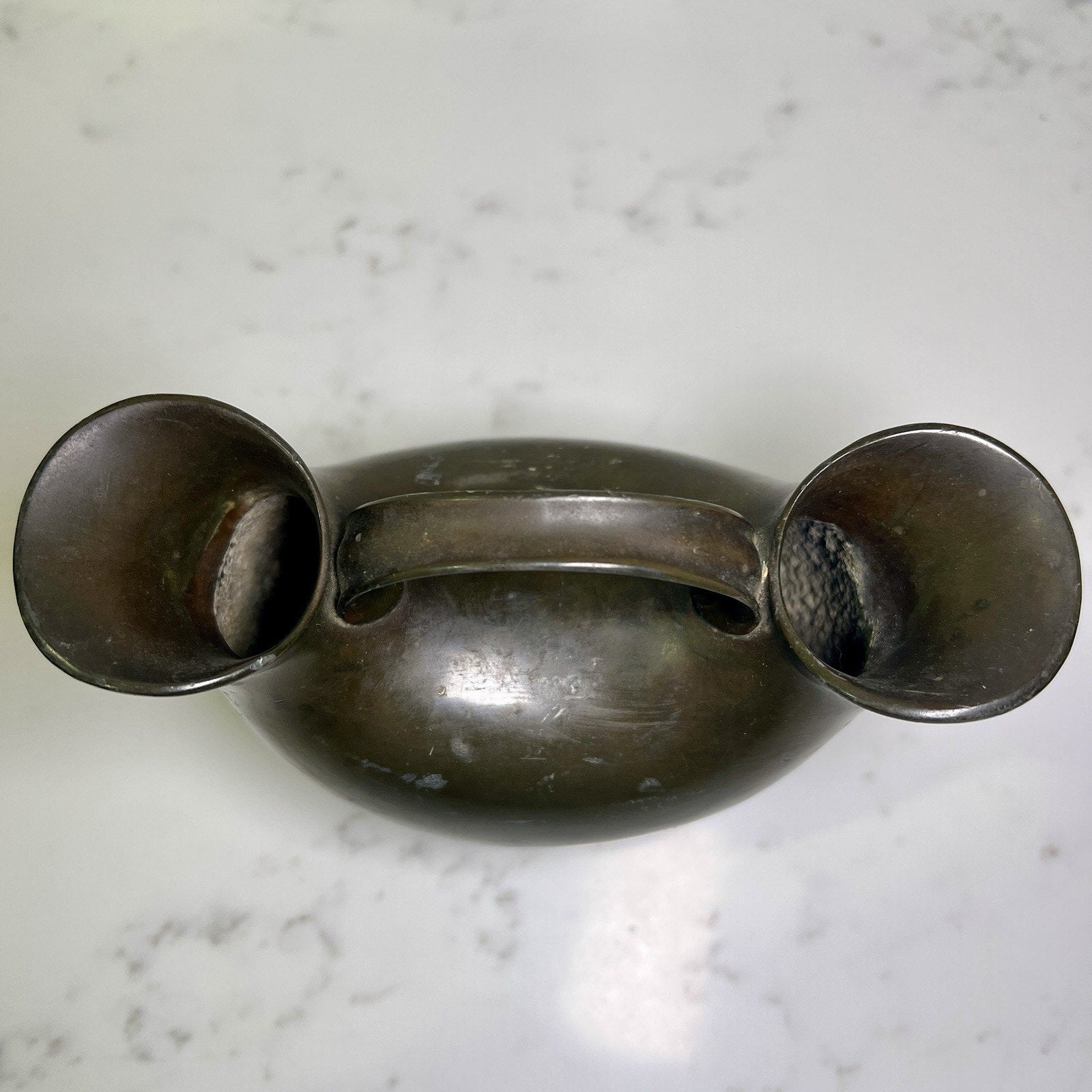 Vintage metal double spout vase  on a marble surface