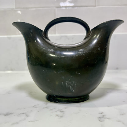 double spout vase on a marble surface with a tiled wall background