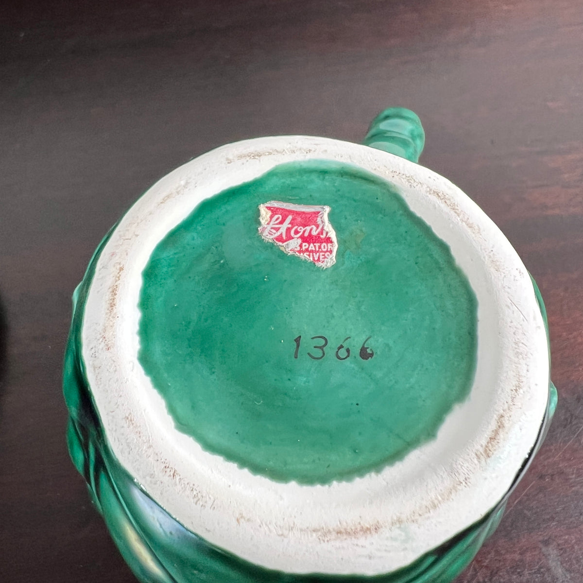The bottom of a vintage green ceramic pitcher or mug, showing a white glazed interior base with a red 'Kenvor' logo sticker and the handwritten number '1366'.