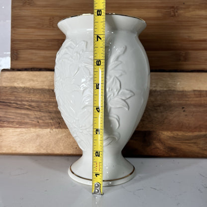 White vase with floral patterns and a tape measure for scale against a wooden background