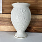 White ceramic vase with floral patterns on a wooden surface