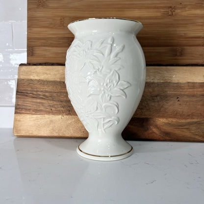 White ceramic vase with floral patterns on a wooden surface
