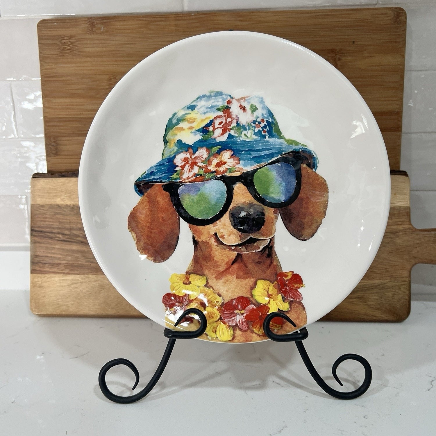 Decorative plate with a dog wearing sunglasses and a hat on a wooden stand.