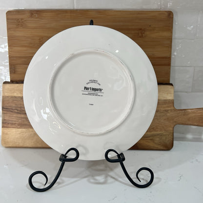 White plate with 'Pier 1' branding on a wooden stand against a tiled wall.