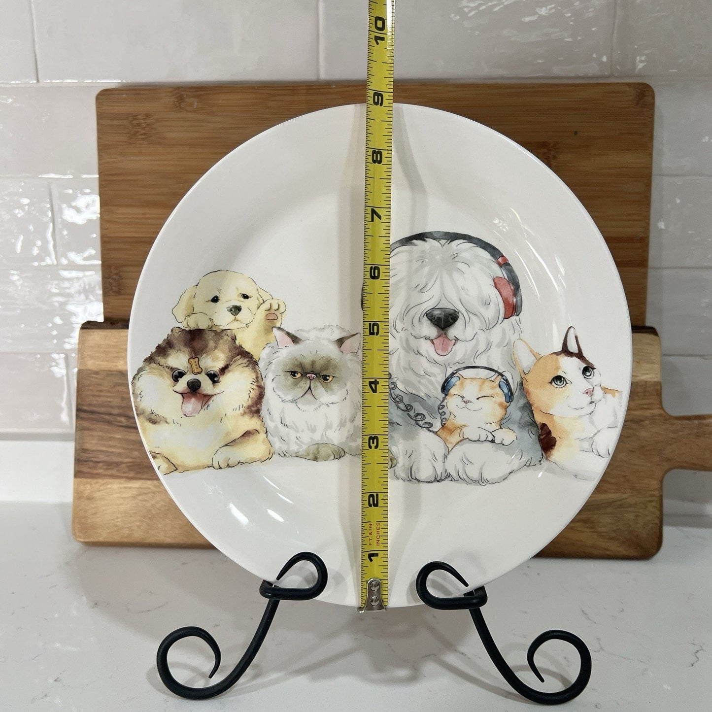 Decorative plate with animal illustrations on a stand, with a tape measure for scale.
