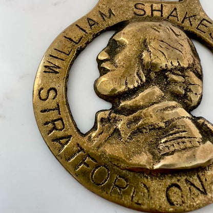 Vintage William Shakespeare horse brass medallion attached to brown leather keychain with brass ring and clip.