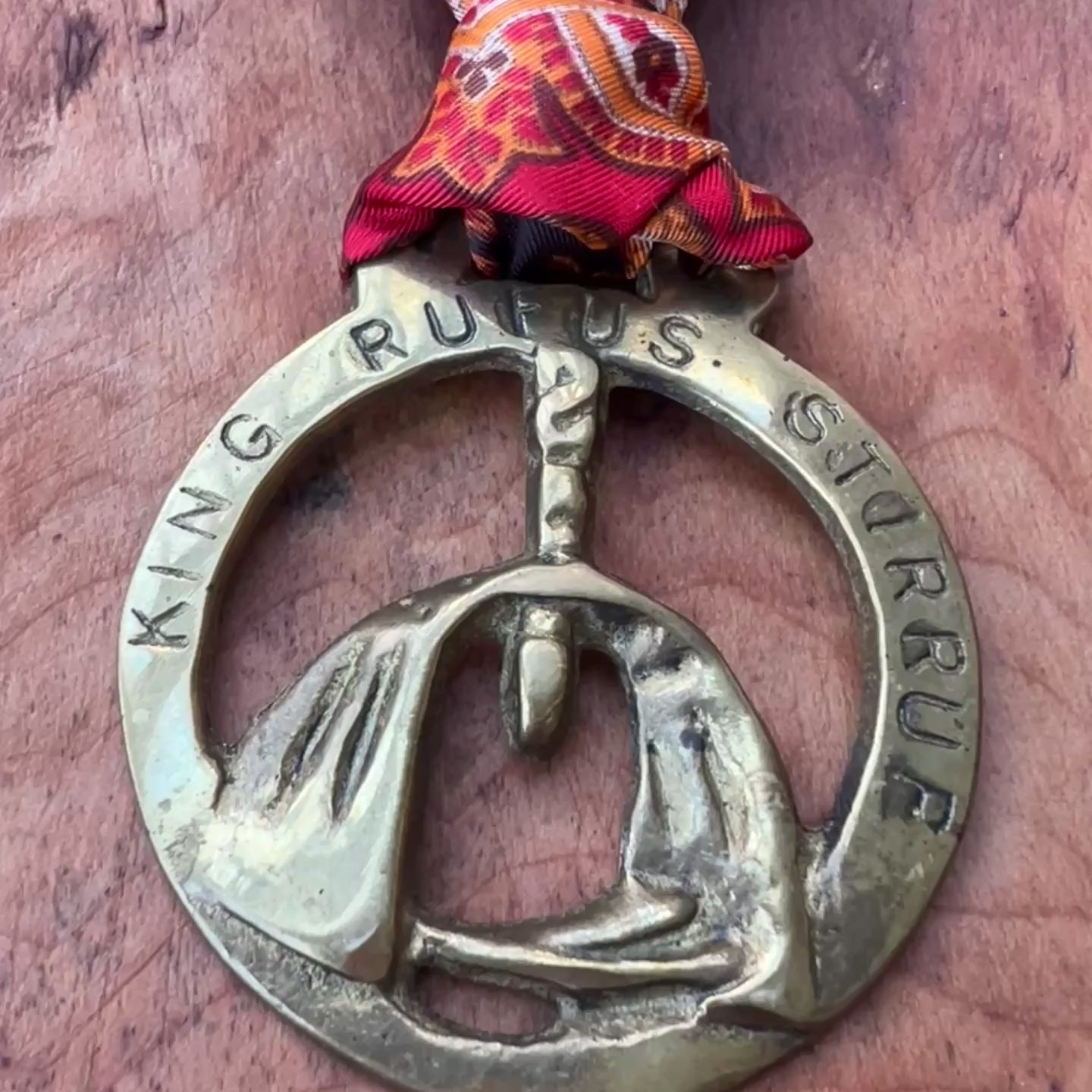 Video Vintage King Rufus Stirrup brass medallion necklace with red paisley scarf, equestrian jewelry on wooden surface